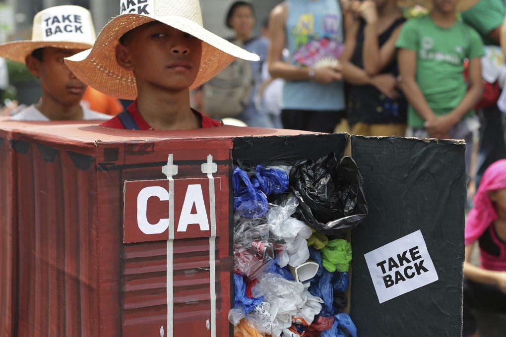 Environmental activists wear a mock container filled with garbage to symbolise the 50 containers of waste that were shipped from Canada to the Philippines two years ago. Photo: AP