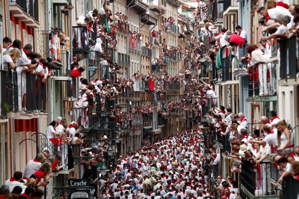 People try to avoid bulls as they run down a street during the traditional San Fermin bull run in Pamplona, Spain on Sunday. Photo: EPA