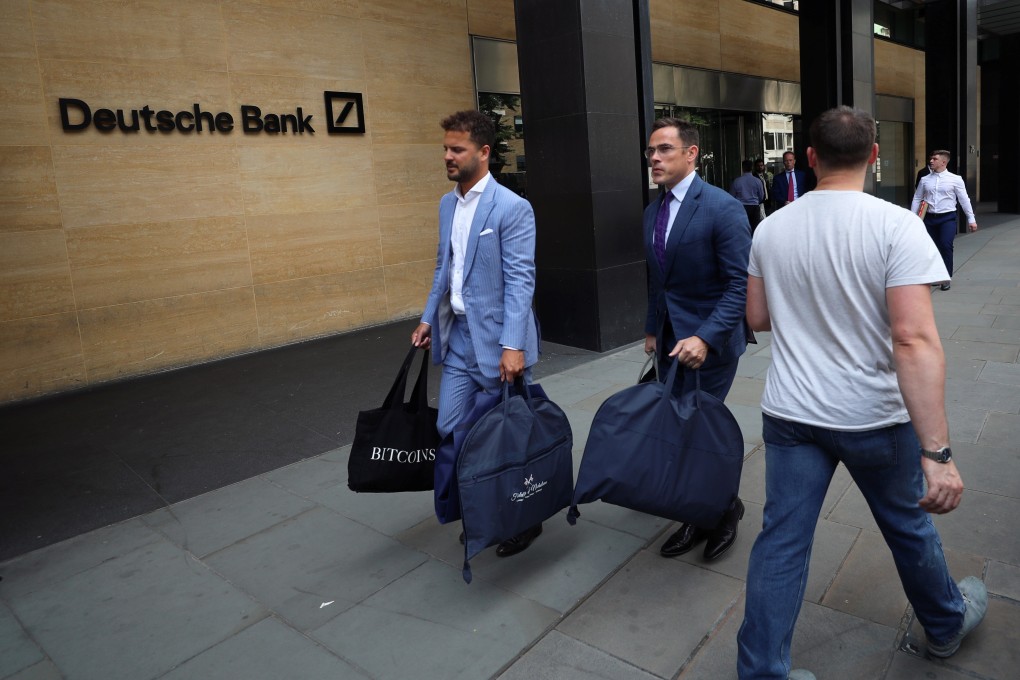 The tailors Alex Riley, left, and Ian Fielding-Calcutt carry suit bags outside the Deutsche Bank building in the City of London. Photo: Reuters