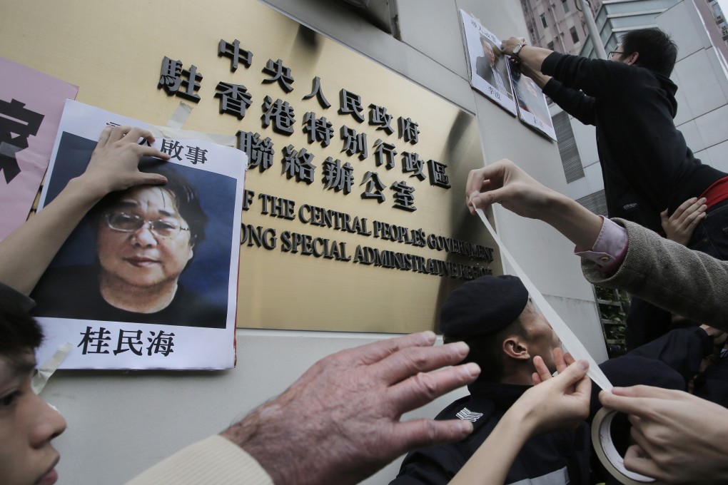 Protesters try to stick photos of missing booksellers, one of which shows Gui Minhai (left), during a demonstration outside the mainland Liaison Office in Hong Kong, on January 3, 2016. Gui, a Swedish citizen, was one of five employees of a Hong Kong bookshop specialising in salacious tales about high-level Chinese politics who were believed to have been spirited to the mainland in late 2015. Photo: AP