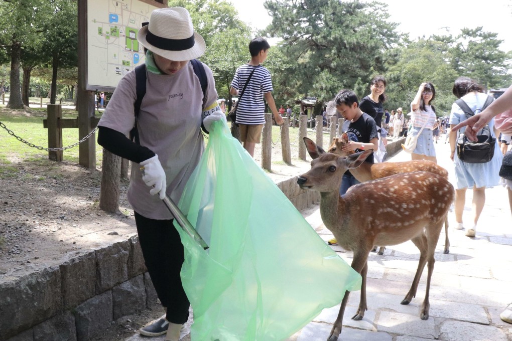 A volunteer picks up plastic products during a clean-up campaign in Nara, Japan, on Wednesday. Photo: Kyodo via AP