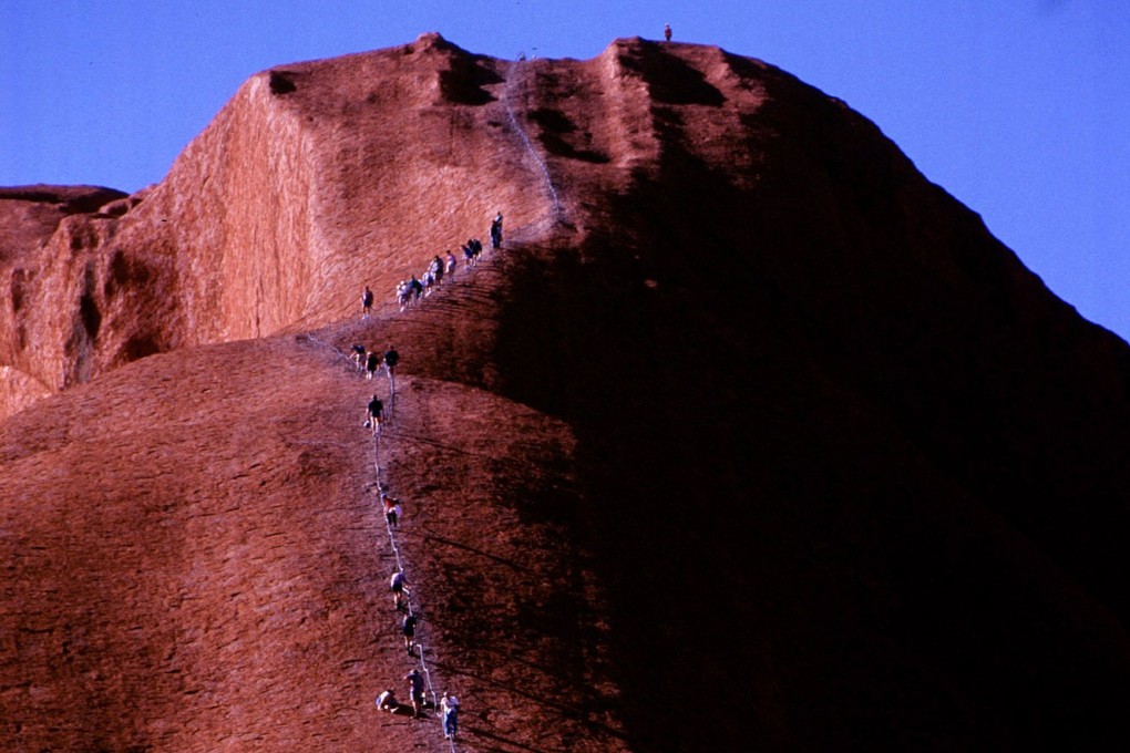 Tourists climb Uluru, one of Australia's top tourist attractions, in July 1997. Photo: Reuters