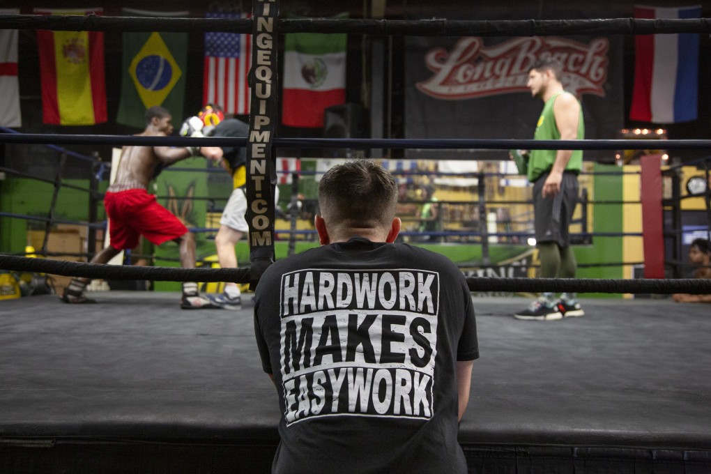 Fighter Cesar Villanueva (centre), 15, watches at ringside as Sincere Brooks (left), 15, and Garrity McOsker, 26, spar in front of trainer Trevor Sambrano (right) at Jackrabbit Boxing Gym, Long Beach, Los Angeles. Photo: Jon Delouz