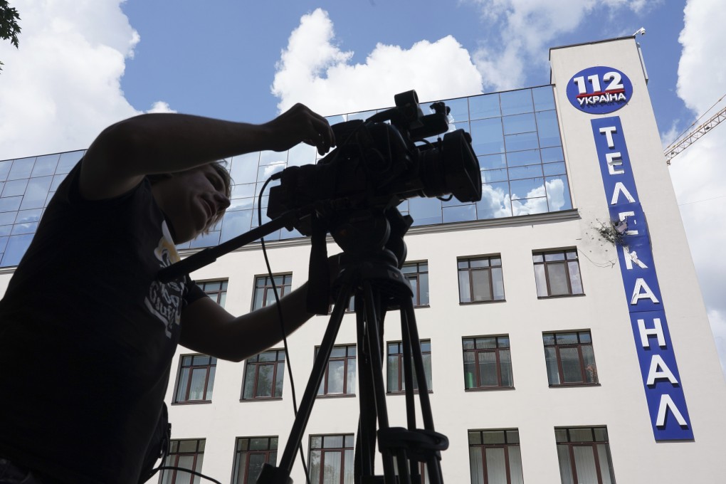 A man sets his camera in front of the damaged building of 112 Ukraine TV channel in Kiev. Photo: AP