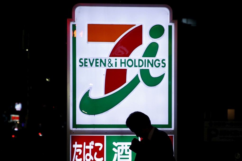 A pedestrian walks in front of a sign at a 7-Eleven convenience store in Tokyo in April 2016. Photo: Reuters