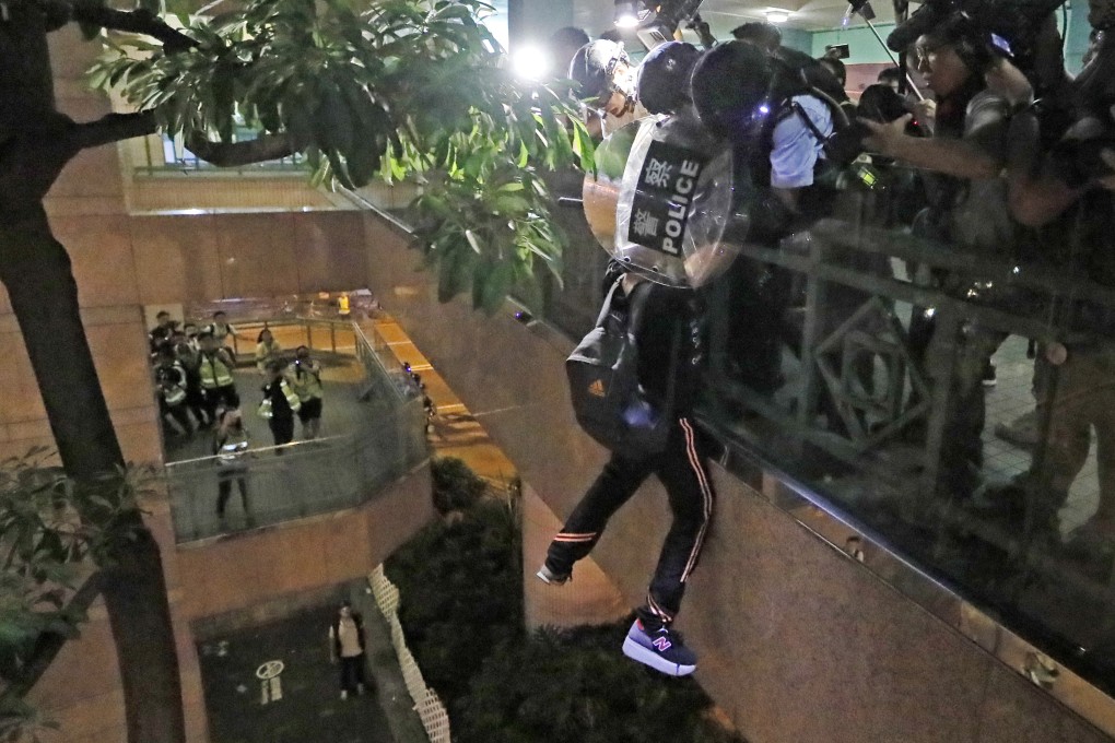 A suspect hangs perilously from a footbridge in Sheung Shui after police tried to speak to him. Photo: AP