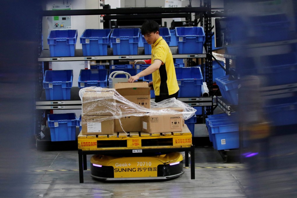 An employee sorts goods moved by a robot at a Suning automated guided vehicle warehouse in Shanghai on May 11, 2018. Photo: Reuters