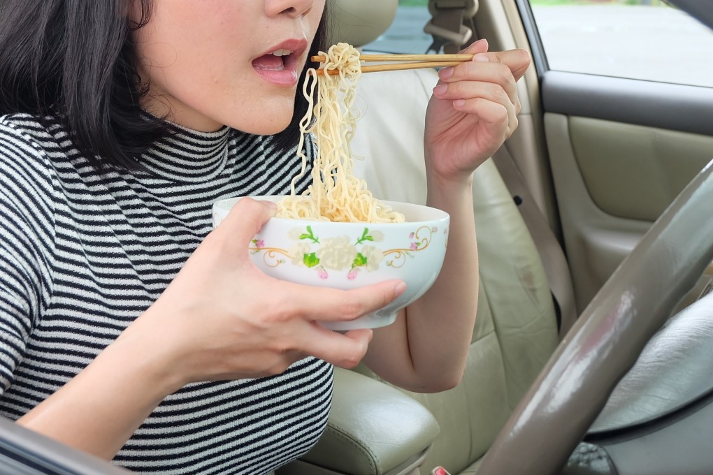 A woman eats noodles in a car. Photo: Shutterstock