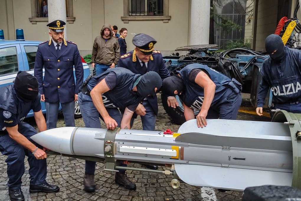 Policemen carry an air-to-air missile seized in northern Italy on Monday. Photo: Italian police via AFP