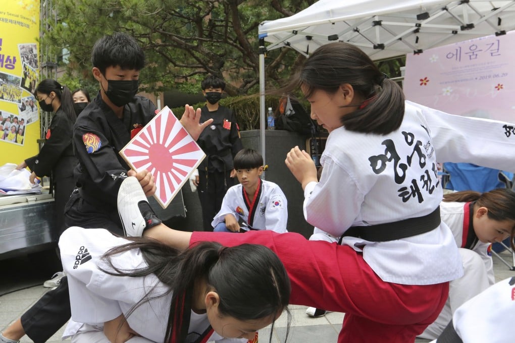 A South Korean student kicks a wooden plate showing a Japanese rising sun flag during a rally in Seoul. Photo: AP