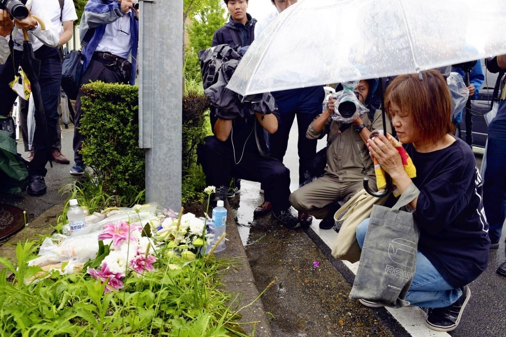 A woman prays after placing flowers near the site of the arson attack. Photo: Japan News-Yomiuri