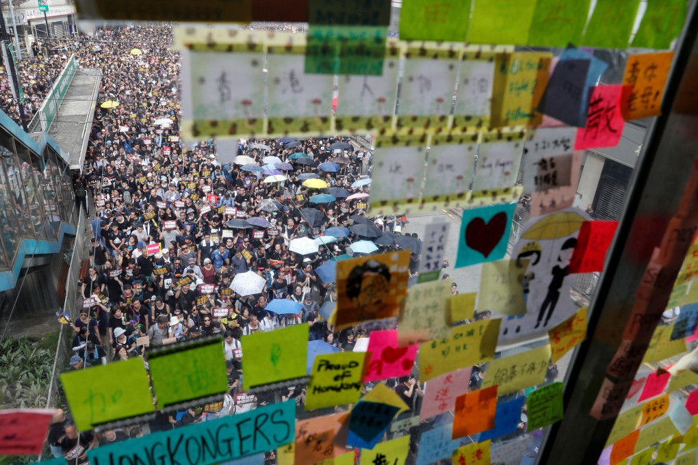 Demonstrators seen through a “Lennon wall” plastered with colourful notes supporting the protests, as marchers rally for democratic reforms in Hong Kong on July 21. Photo: Reuters