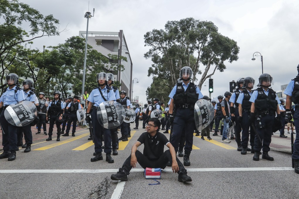 A protester sits on the street in front of riot police as demonstrators march in Sha Tin to demand the total withdrawal of the extradition bill on July 14. Photo: Edmond So
