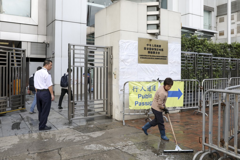 A worker continues to clean-up the mess left by protesters outside the liaison office in Sai Ying Pun. Photo: Nora Tam
