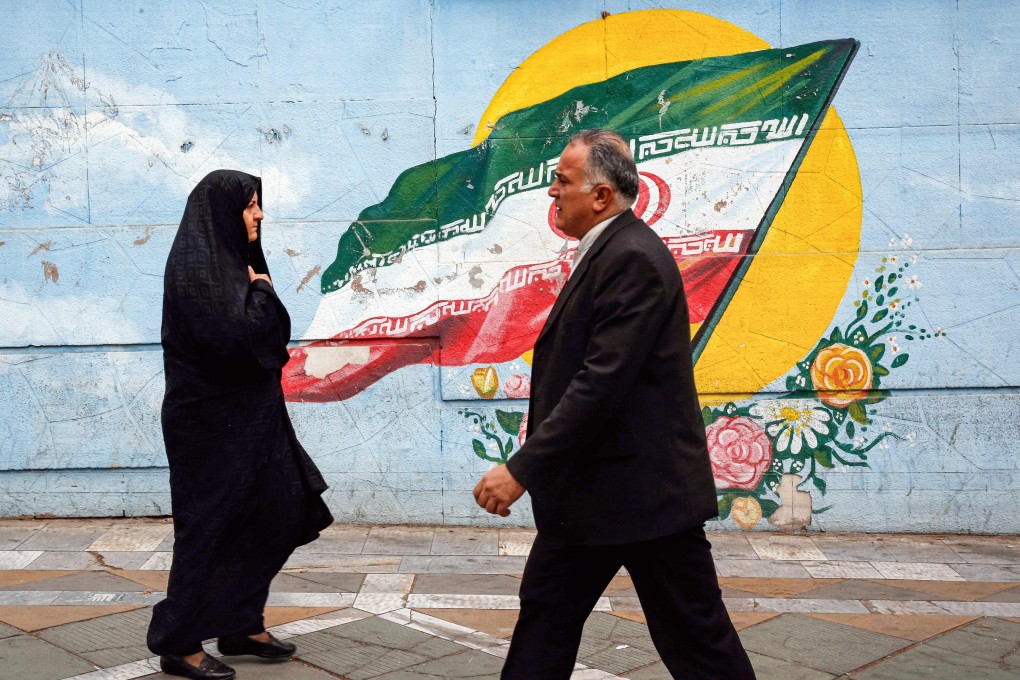 People walk past a mural depicting an Iranian flag in Tehran on Monday. Photo: AFP