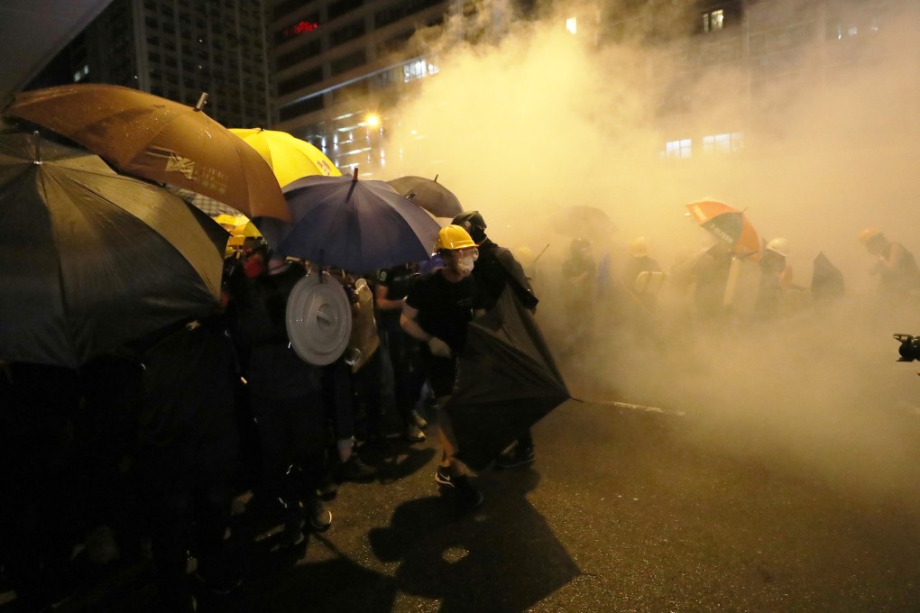 Protesters try to fight off the effects of tear gas fired by police on Sunday. Photo: Sam Tsang