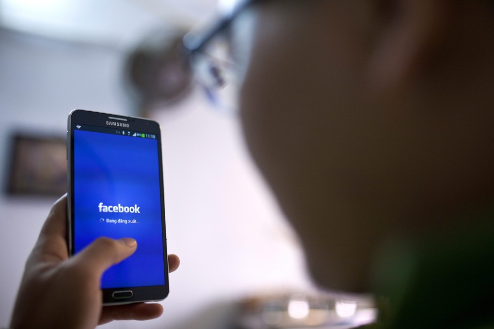 A man uses the Facebook app on his phone in a cafe in Hanoi. Photo: EPA