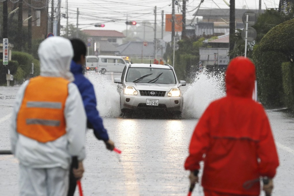 A car drives through a flooded road after heavy rain in Miyakonojo City. Photo: AP