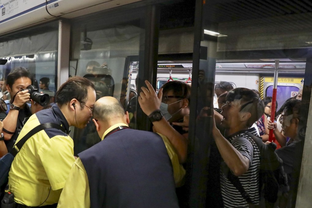 Protesters prevent the doors of a train closing as MTR staff try to stop them at Admiralty station. Photo: Nora Tam