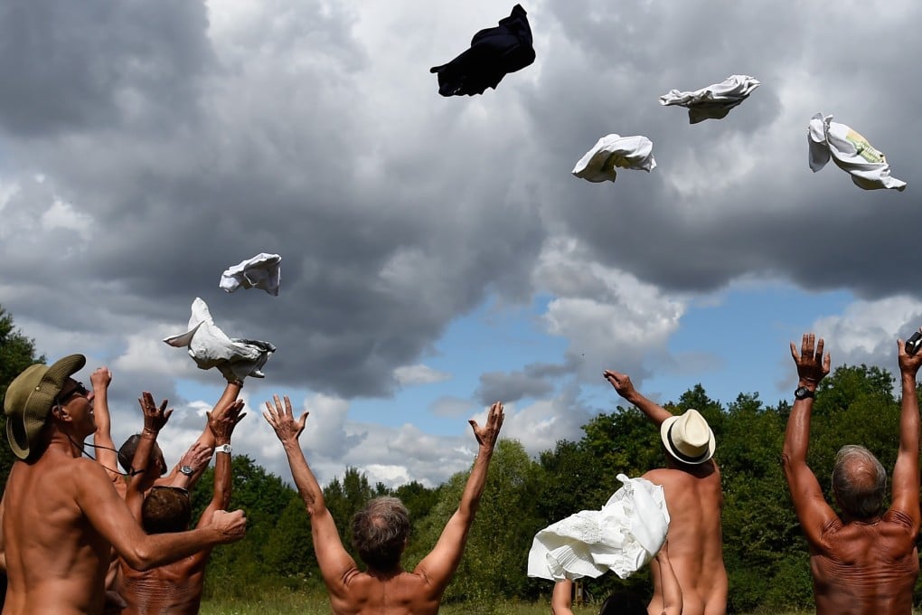 People throw their clothes in the air to celebrate the opening of the Bois de Vincennes nudist area in 2017. File photo: AFP