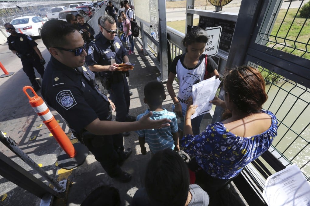 A United States Customs and Border Protection officer checks the documents of migrants before they are taken to apply for asylum in the United States. Photo: AP Photo