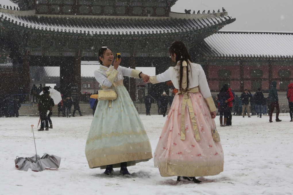 A woman takes a picture in the snow in Seoul, South Korea. Photo: AP