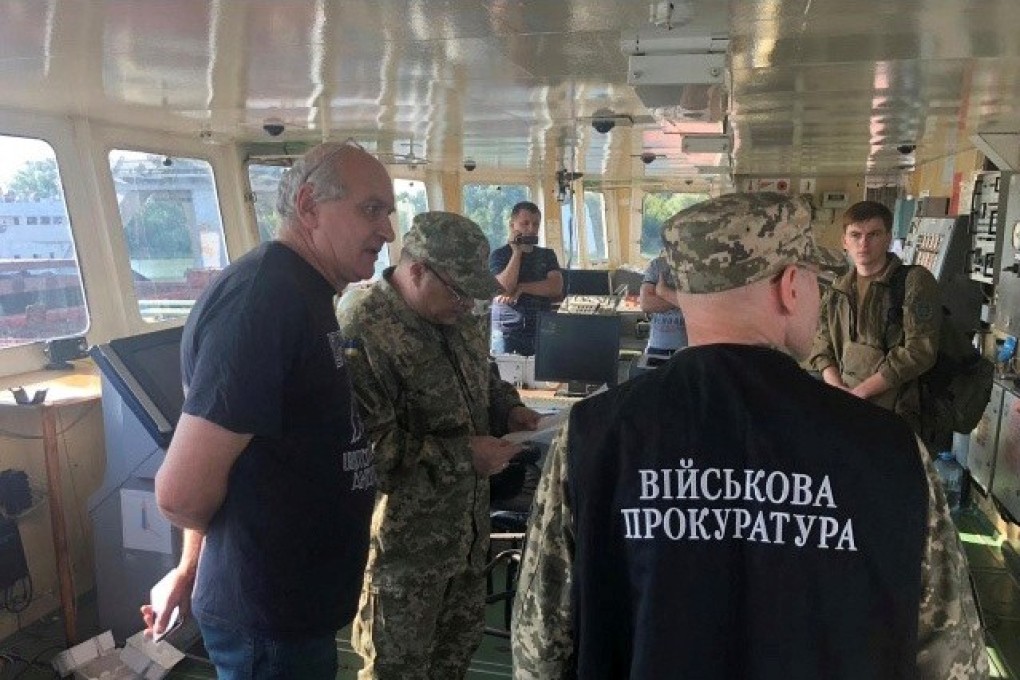 Officers of the Ukrainian security services surround a crew member (left) of the Russian tanker. Photo: Handout via Reuters