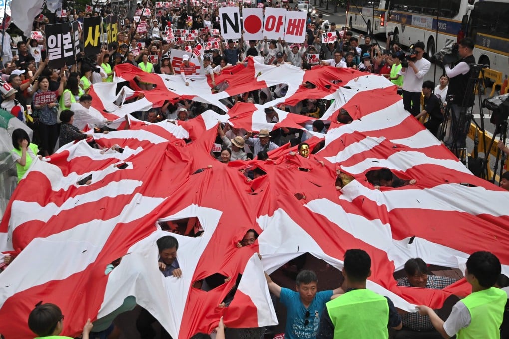 South Koreans tear a huge Japanese rising sun flag during a rally in Seoul. Photo: AFP
