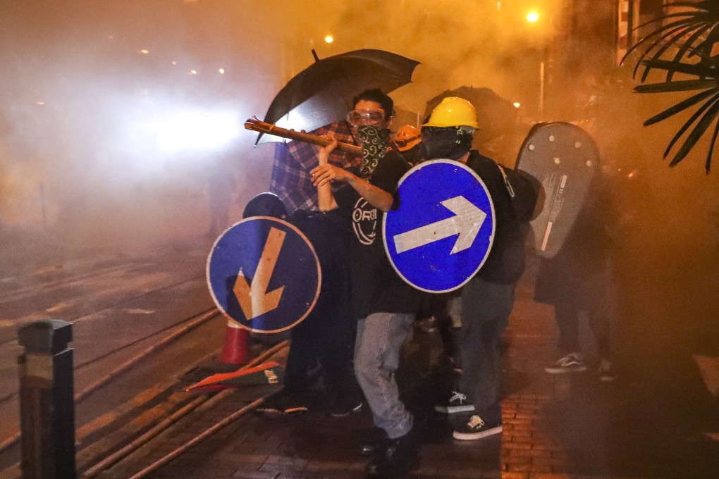 Protesters on Sunday fight through tear gas as they clash with riot police near Beijing’s liaison office in Sai Ying Pun. Photo: Edmond So
