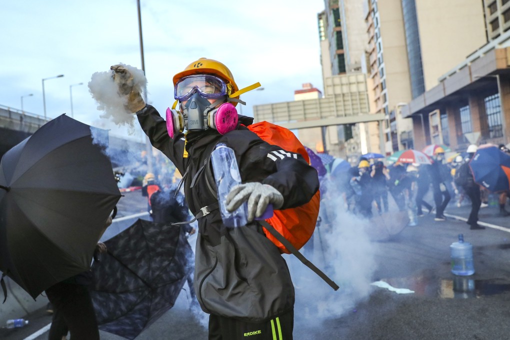 A protester throws a tear-gas canister back at riot police, as demonstrators march towards Beijing’s liaison office in Sai Ying Pun on July 28. Photo: Sam Tsang