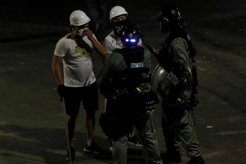 Riot police talk to men wearing white T-shirts and carrying rods in Yuen Long on the early hours of July 22. Photo: Reuters
