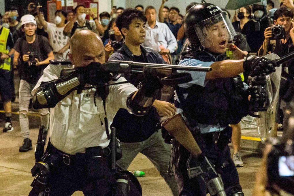 The officer in Kwai Chung points his gun, loaded with beanbag rounds, at the protesting crowd. Photo: AFP
