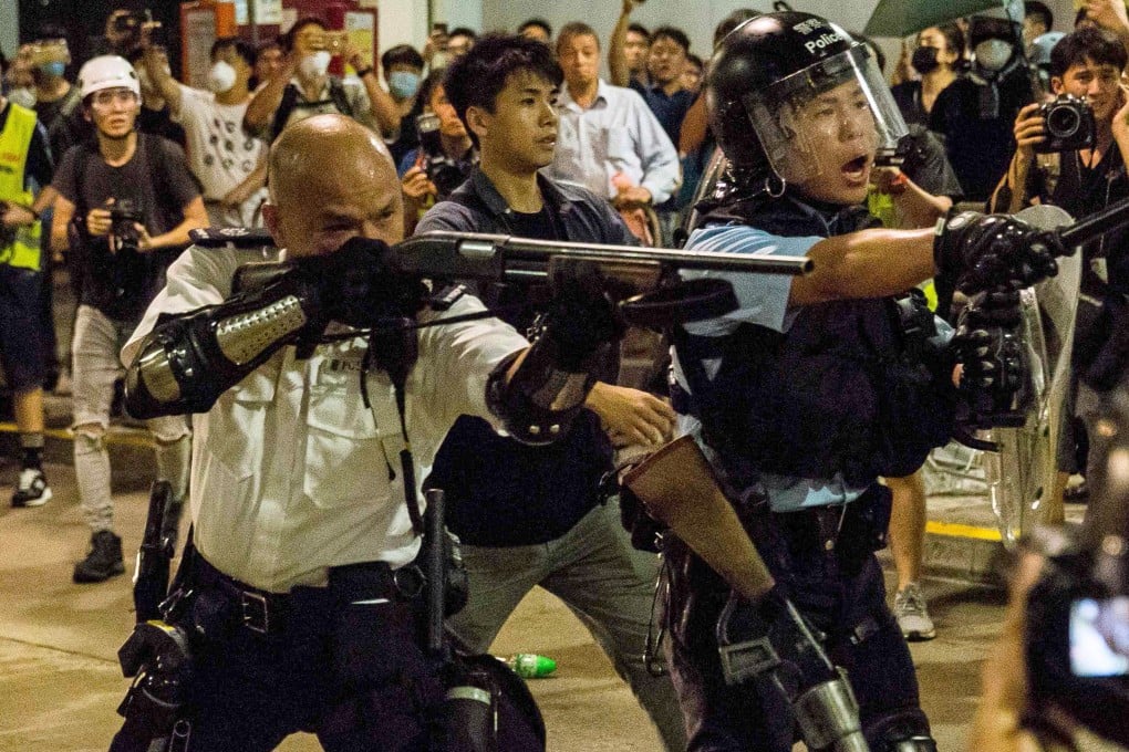 The officer in Kwai Chung points his gun, loaded with beanbag rounds, at the protesting crowd. Photo: AFP