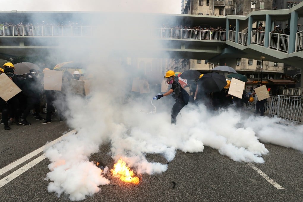 An anti-government protester tries to extinguish tear gas during a clash with riot police in Hong Kong on Saturday. Photo: Sam Tsang