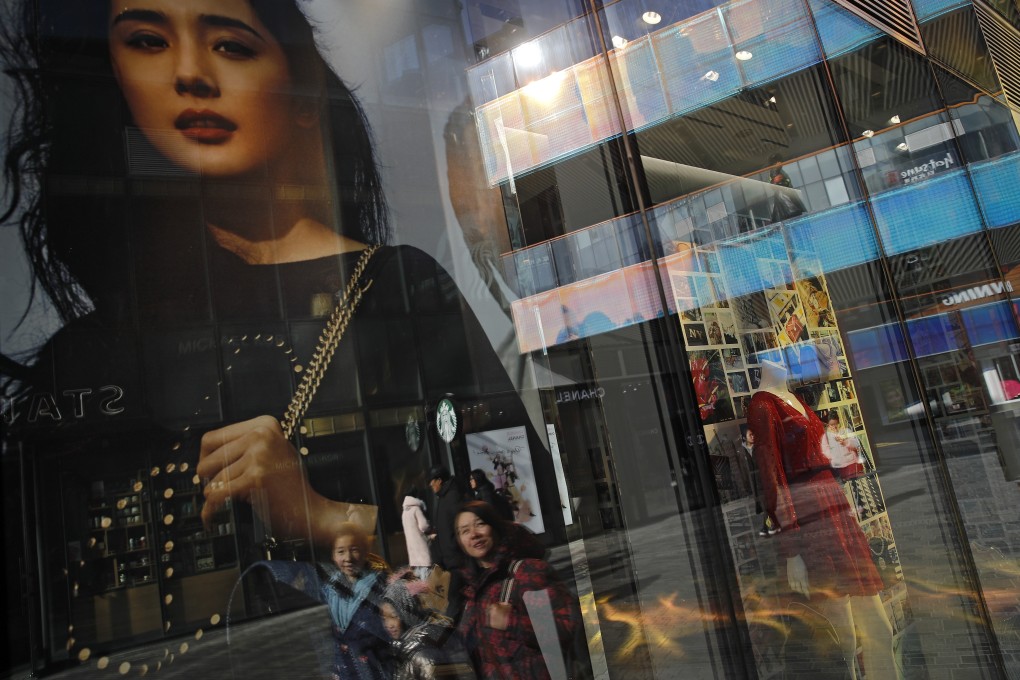 Shoppers are reflected on the window panels of a fashion boutique at a popular shopping mall in Beijing. Despite economic headwinds, China’s retail sales jumped up 9.8 per cent in June, their best performance in more than a year. Photo: AP