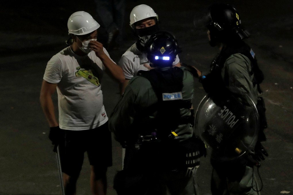 Men in white T-shirts and carrying poles talk to riot police in Yuen Long after anti-extradition bill demonstrators were attacked at the area’s MTR station. Photo: Rueters