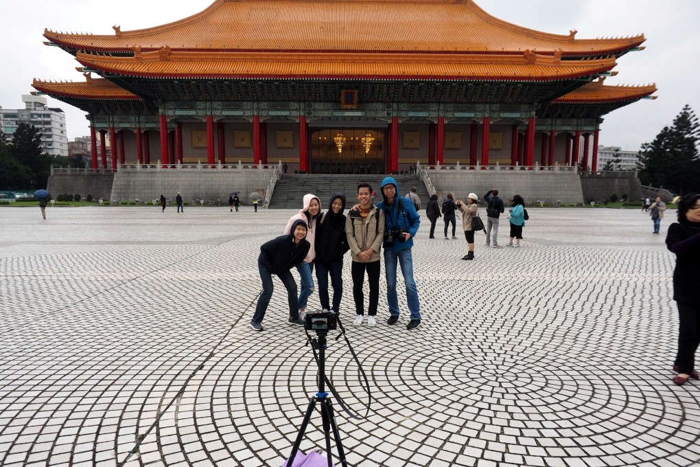 Tourists pose for a picture in front of the National Concert Hall in Taipei. Beijing this week announced curbs on visits to the island. Photo: EPA-EFE