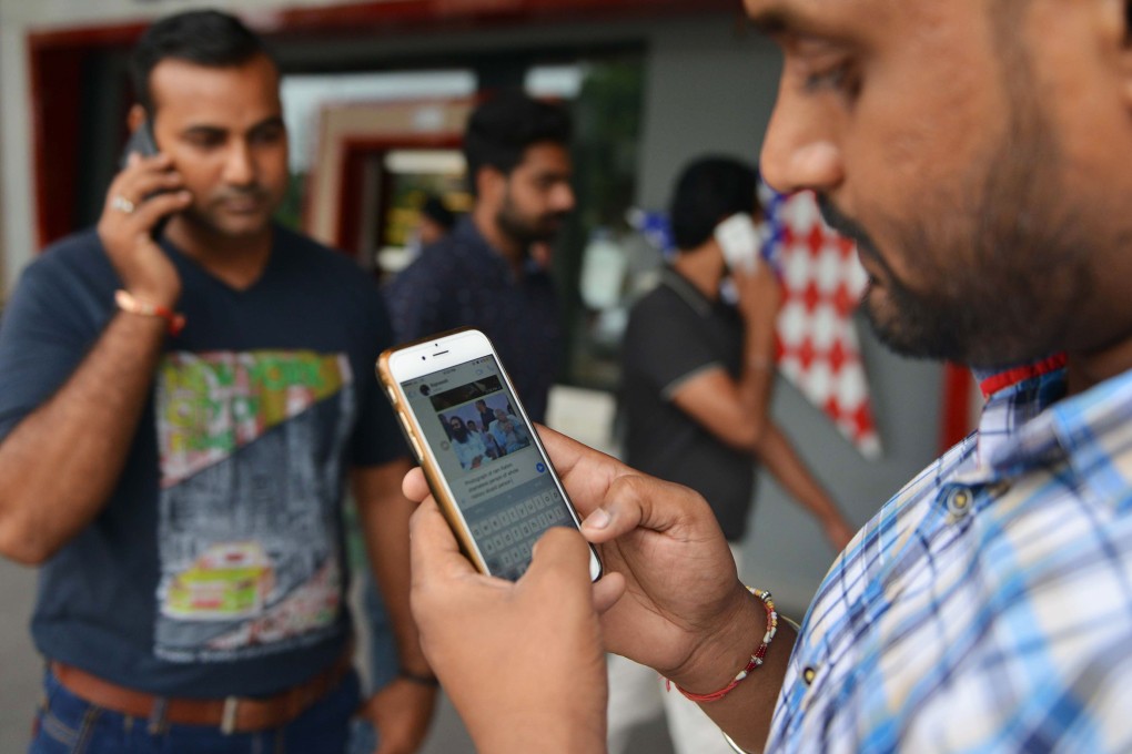 Indian men use their mobile phones in the street. Photo: Agence France-Presse
