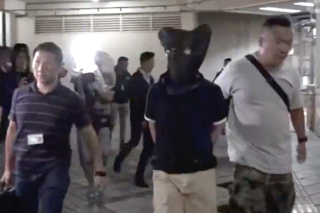 Police escort those arrested in the industrial building. Photo: RTHK