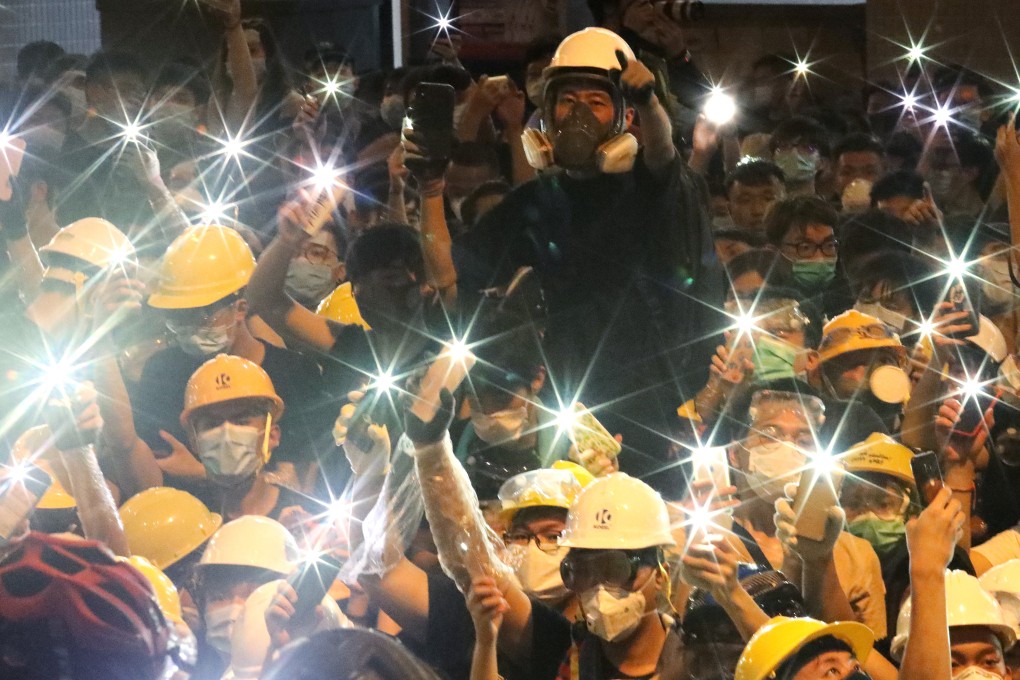 Protestors raise up their mobile flashlights outside police headquarters in Wan Chai. Photo: Felix Wong