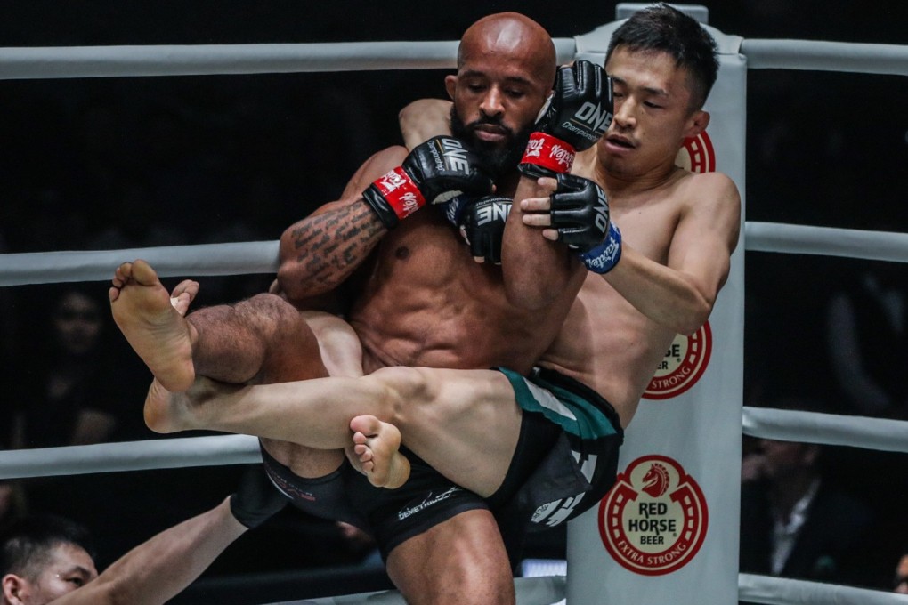 Tatsumitsu Wada gets hold of Demetrious Johnson in the corner of the ring. Photos: One Championship