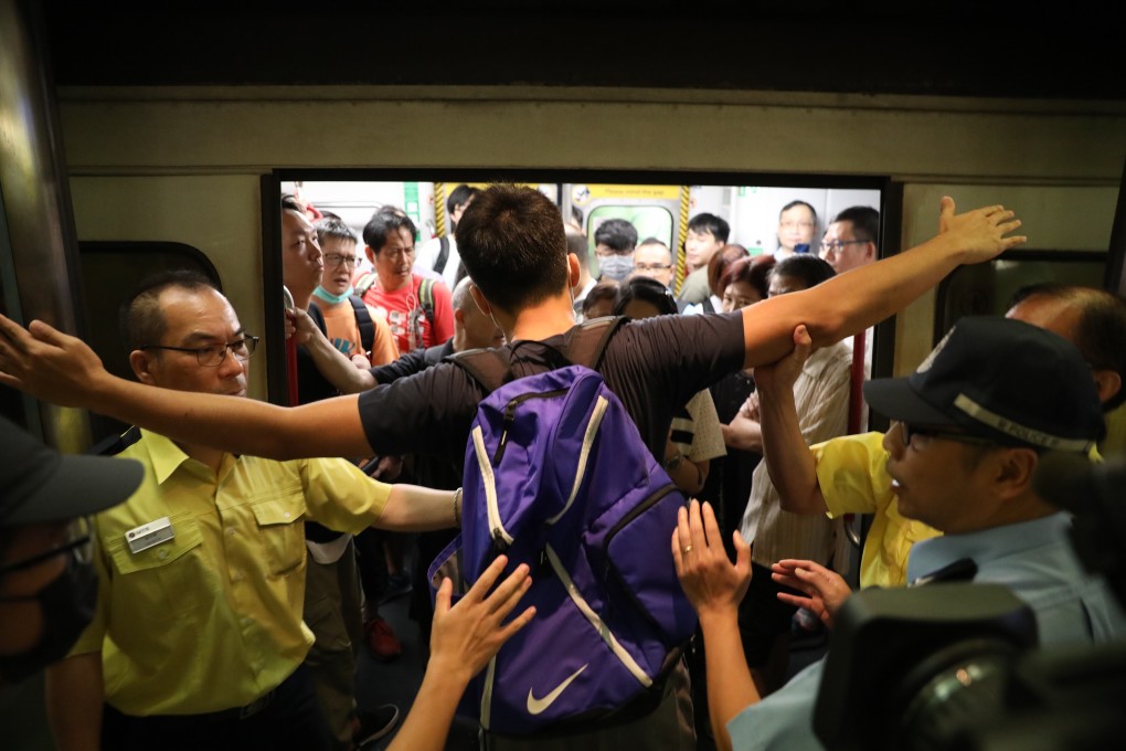 A protester prevents a train from leaving Tiu Keng Leng MTR station. Strike organisers said traffic disruptions would start Monday morning. Photo: Nora Tam