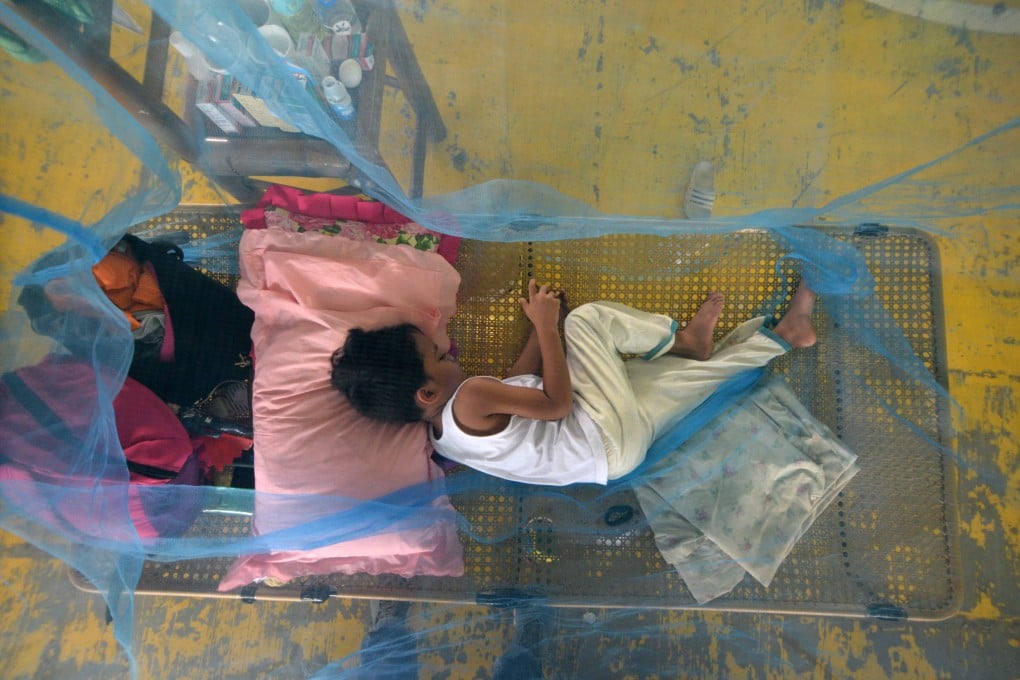 A boy suffering from dengue fever rests inside a mosquito net in the town of Maasin, the Philippines. Photo: EPA