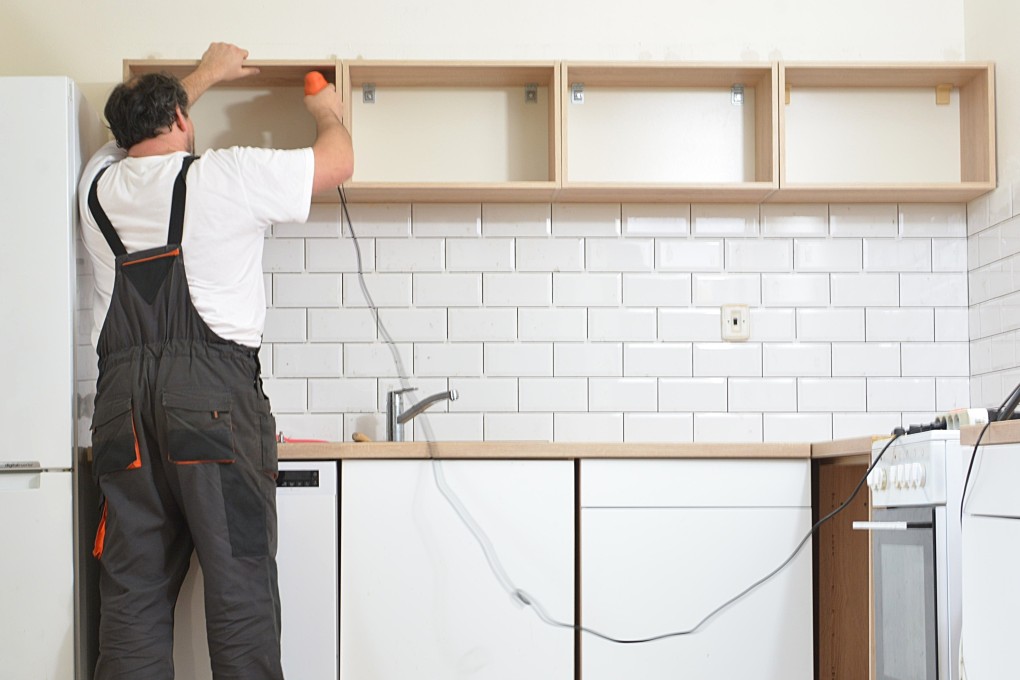 A man installing kitchen cabinets, one of the items covered by the preliminary duties. Photo: Shutterstock