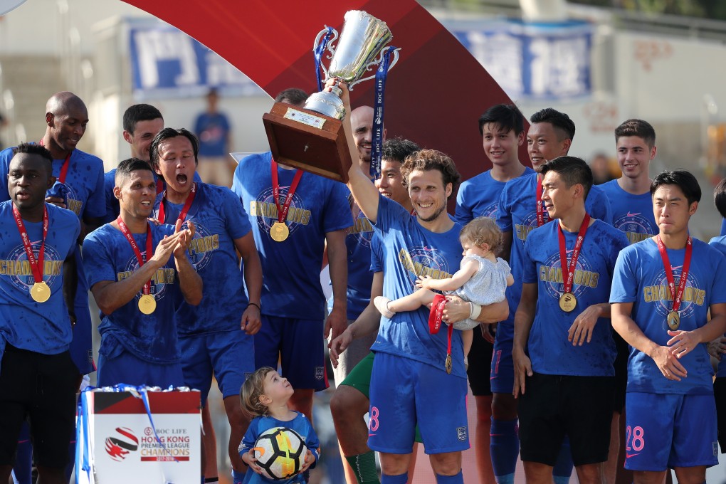 Diego Forlan lifts the Hong Kong Premier League trophy while carrying baby daughter Luz, while his son Martin looks on in May 2018. Photo: Winson Wong