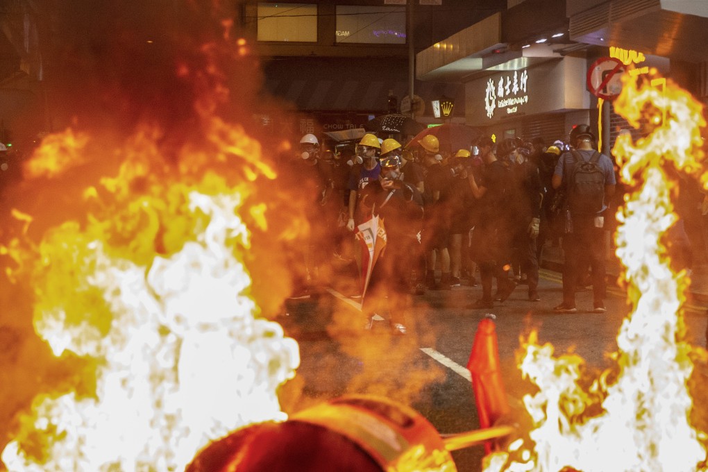 Protesters seen through blazing rubbish bins in Hong Kong’s Causeway Bay on Sunday. Photo: EPA