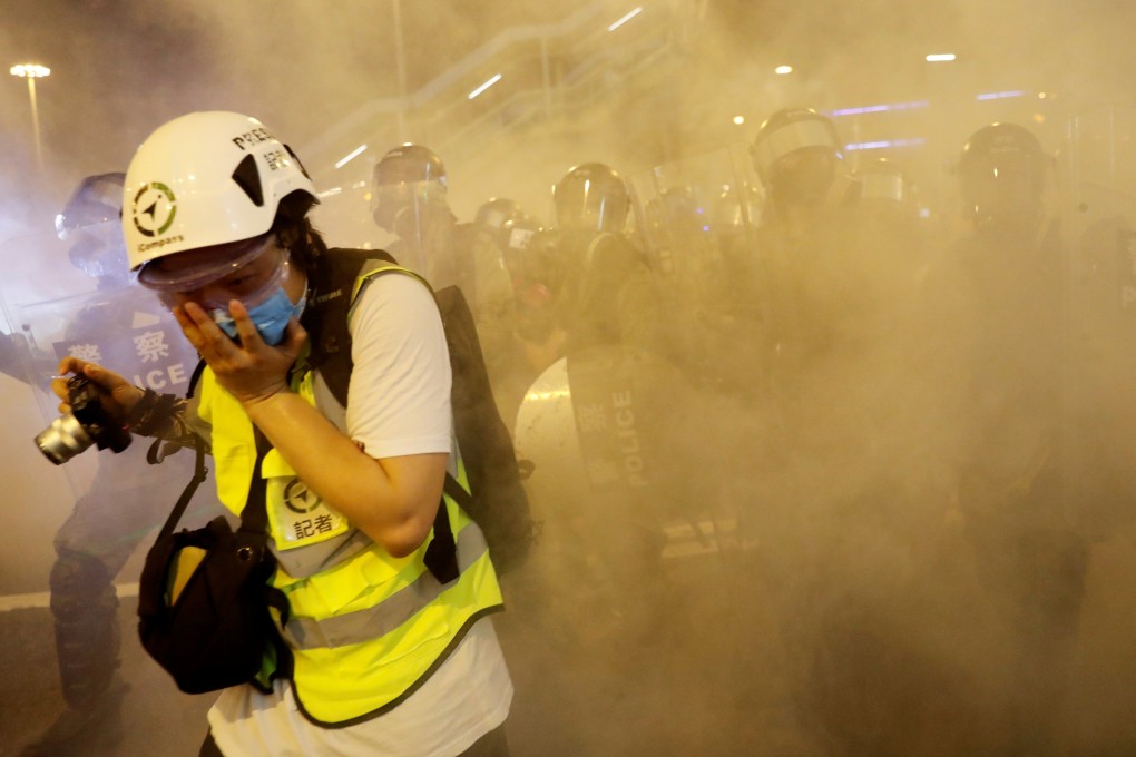 A journalist covers her face after police officers fired tear gas toward extradition bill protesters during a protest in Hong Kong on Sunday. Photo: Reuters