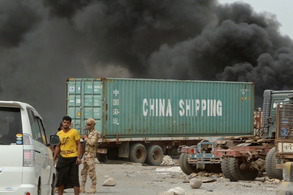 Members of UAE-backed forces stop cars on a street as smoke billows from a car service shop during clashes in Aden, Yemen. Photo: Reuters