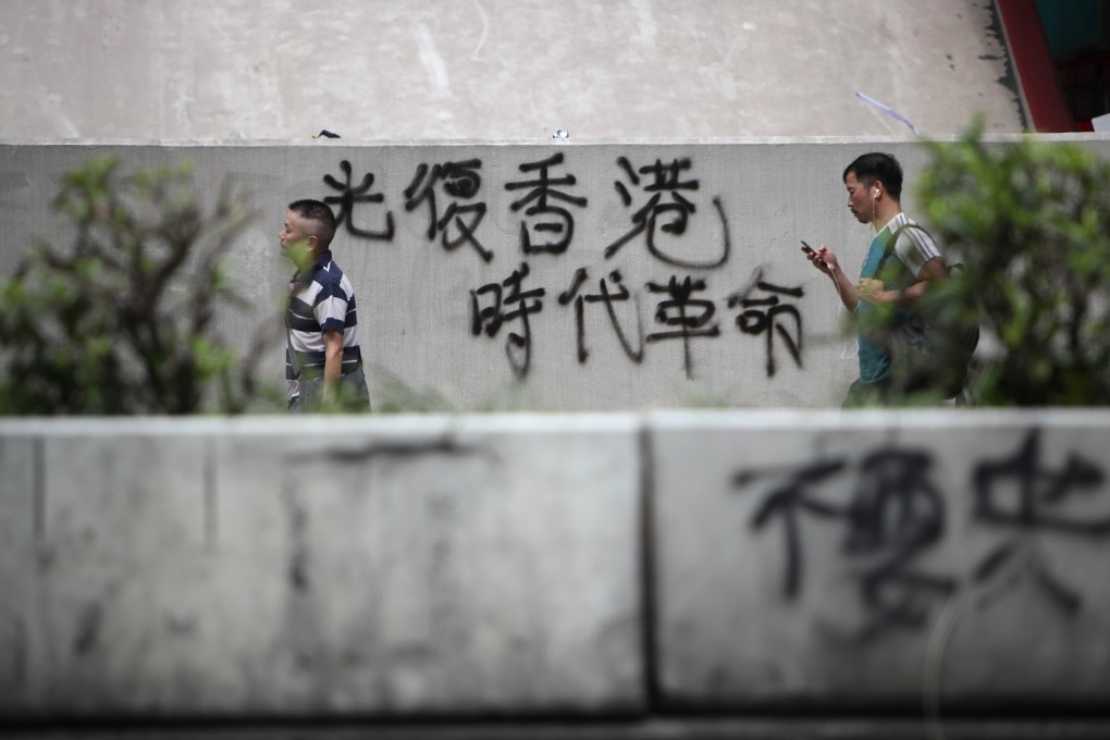 People walk past a wall on which the slogan “liberate Hong Kong, revolution of our times” has been graffitied on Nathan Road, Mong Kok, a day after the August 5 citywide strike. Photo: Winson Wong