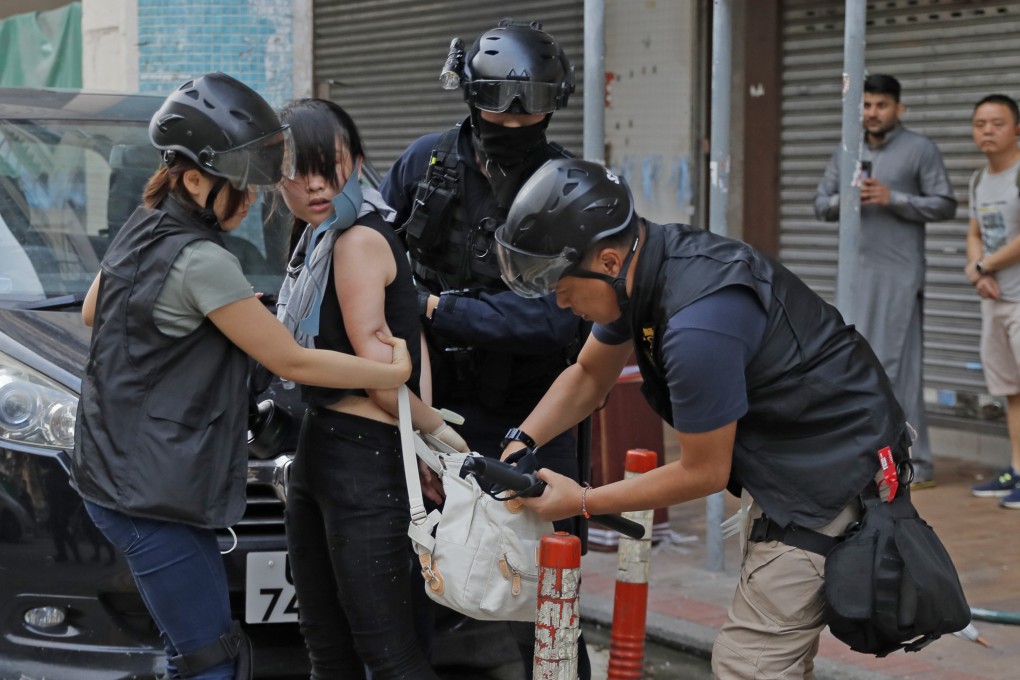 Policemen search a protester’s bag in Hong Kong. Photo: AP
